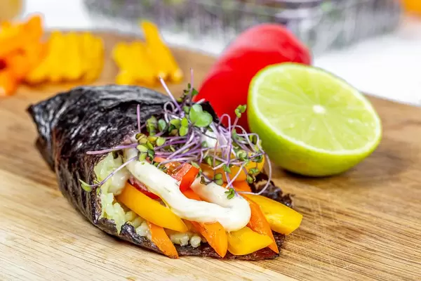 Fresh vegetable roll with micro-greens of cabbage and sauce on the kitchen board