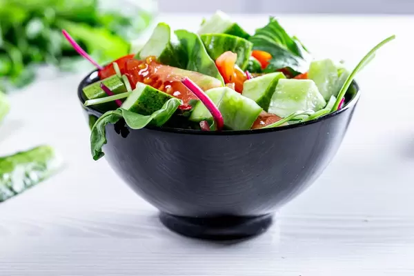 Fresh vegetable salad with arugula, spinach, tomatoes and cucumbers in a black mask (Flip 2019)