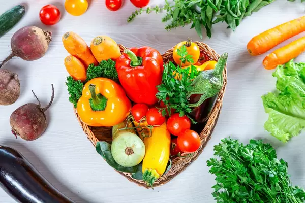 Fresh vegetables in the basket and around it on a white wooden background. Top view (Flip 2019)