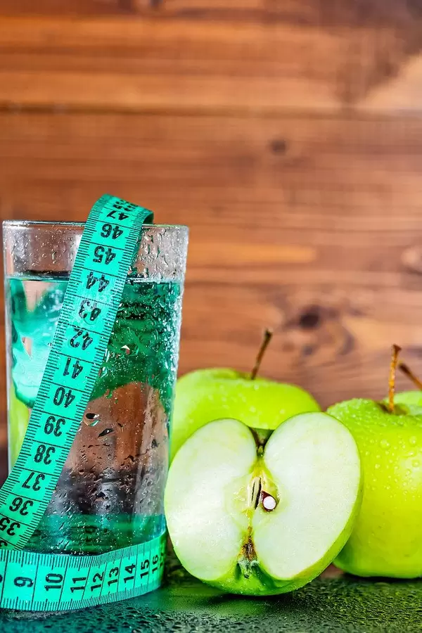 Fresh washed apple, water drops on a glass and a measuring tape