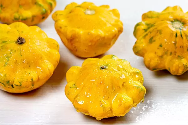 Fresh yellow patisson with water drops on white wooden background (Flip 2019)