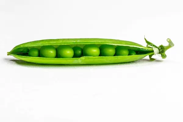 Fresh young green peas in open pods on a white background
