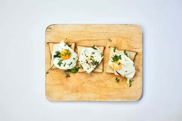 Freshly fried eggs with herbs on cutting board