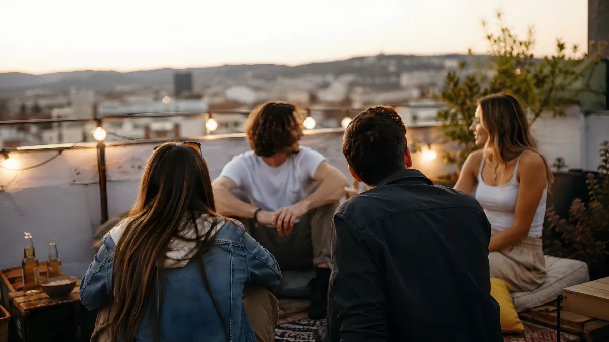 Freunde genießen Abend auf Dachterrasse bei Sonnenuntergang