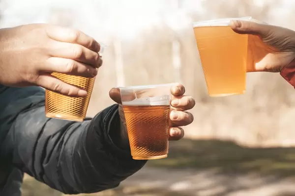 Freunde mit Bier in der Hand vor einem verschwommenen Natur-Hintergrund