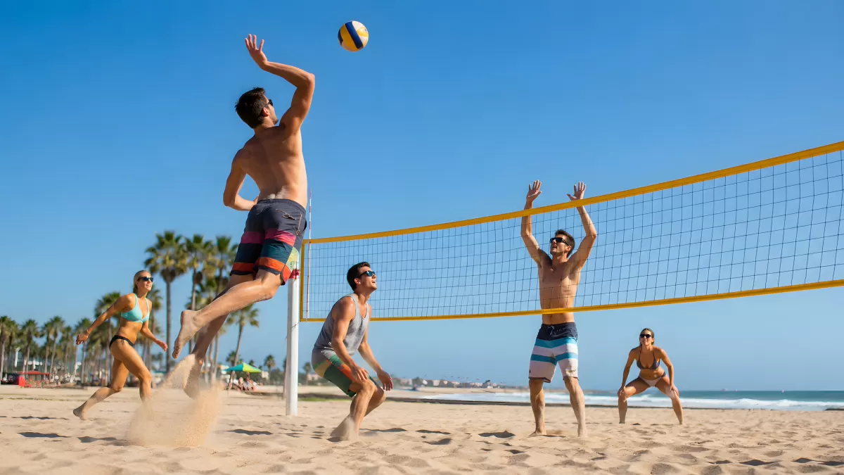 Freunde spielen Beachvolleyball am sonnigen Sandstrand