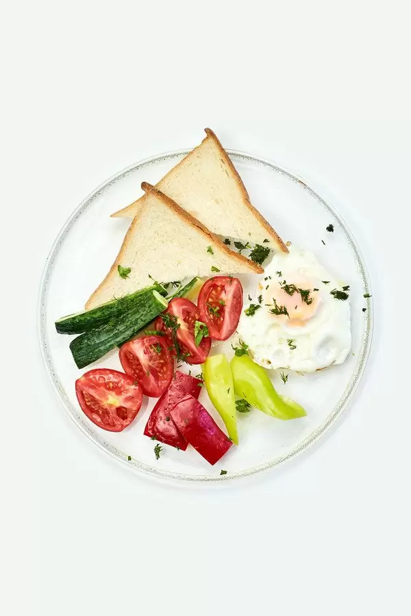 Fried breakfast with egg, tomatoes, bell pepper cucumber and toasts