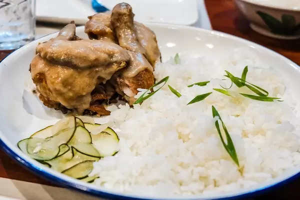 Fried chicken covered in gravy served with rice