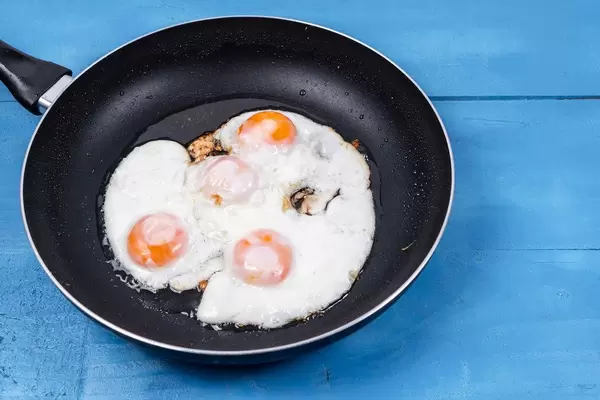 Fried Eggs in the black frying pan above wooden table (Flip 2020)