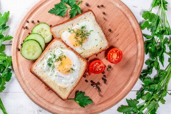 Fried eggs in toast bread with spices, vegetables and herbs