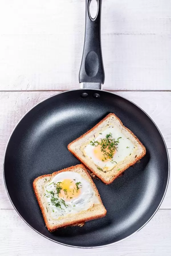 Fried eggs with bread and herbs in a frying pan