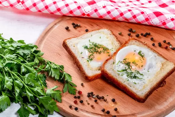 Fried eggs with toast bread on wooden kitchen Board