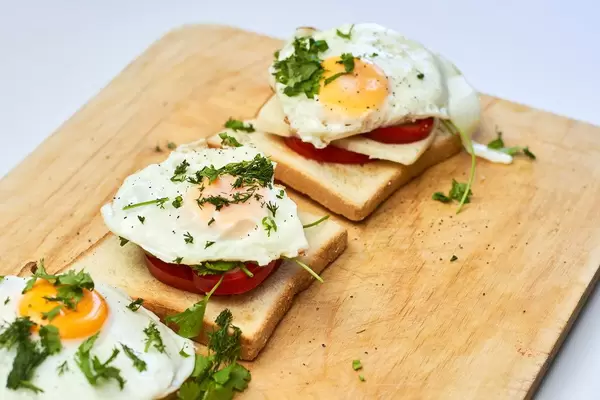 Fried eggs with toasted bread and parsley on wooden cutting board