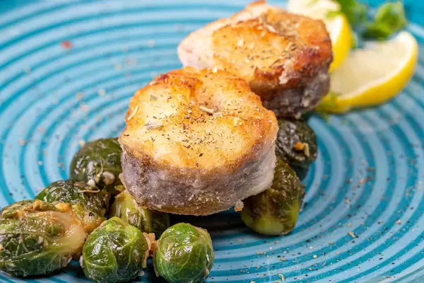 Fried fish with Brussels sprouts and spices closeup (Flip 2019)