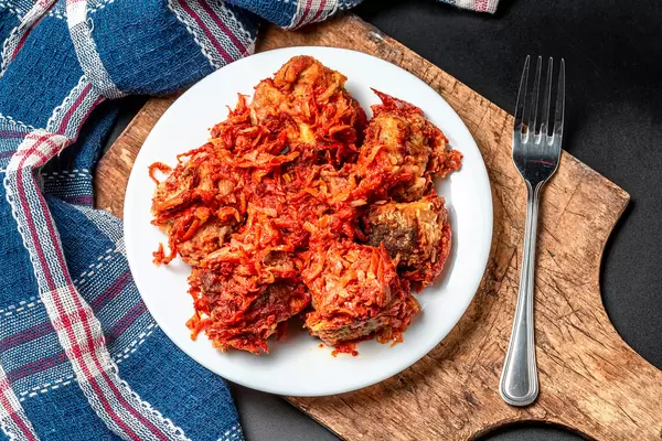 Fried hake with tomato sauce and vegetables on an old wooden kitchen board, top view