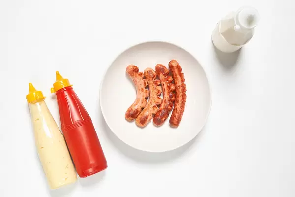 Fried hot-dog sausages and sauces on white