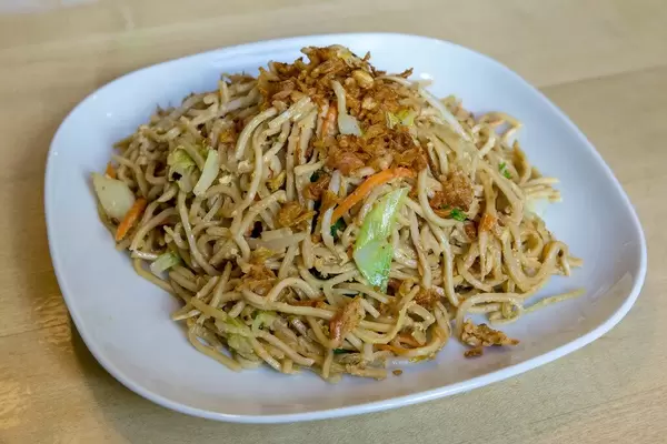 Fried noodles with egg, carrots and leek, served on a light plate as a vegetarian dish.