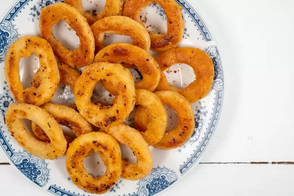 Fried Onion Rings served on the white plate above wooden table (Flip 2020)