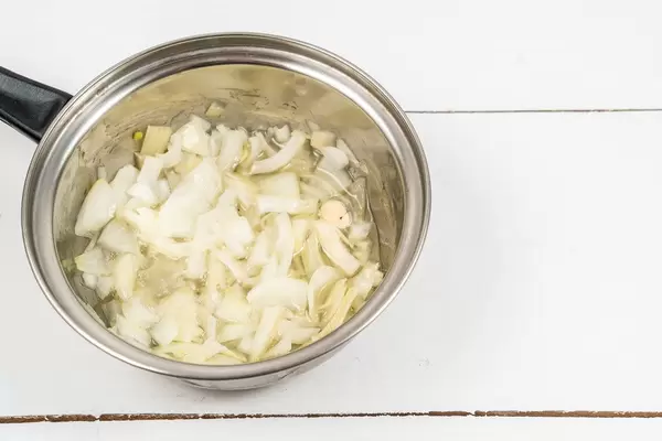 Fried Onions in the metal pot on the wooden table (Flip 2020)