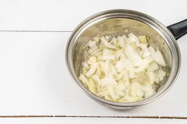 Fried Onions in the metal pot on the wooden table