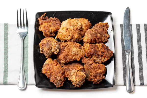 Fried pork liver on black plate, top view