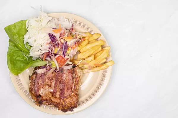 Fried Pork Meat in Bacon with cabbage salad and french fries