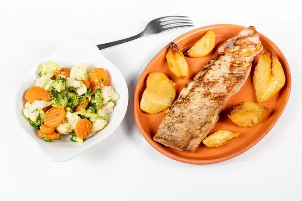 Fried Pork Steak with Potatoes and Vegetable Salad isolated on a clay plate