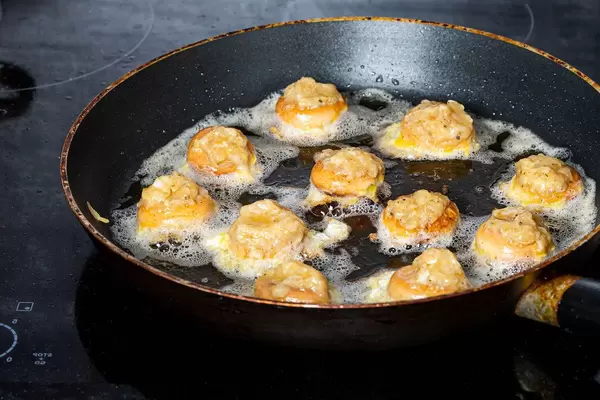 Fried stuffed bagels in a frying pan on an electric hob (Flip 2019)
