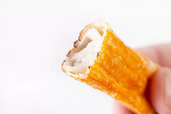 Fried Surimi Sticks in the hand above white background (Flip 2019)