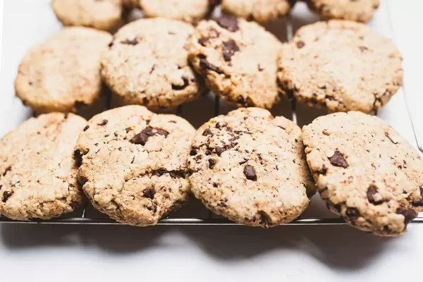 Frisch gebackene, vegane Schokoladenkekse mit Schokoladestücken auf Backrost