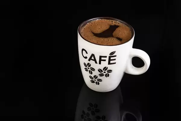 Frisch gebrühter schwarzer Kaffee in weißer Kaffeetasse isoliert vor schwarzem Hintergrund