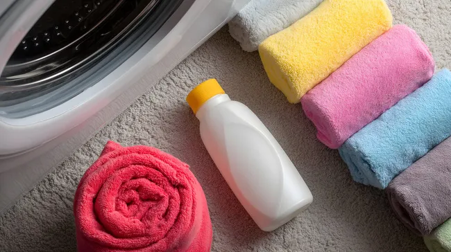 Frisch gewaschene Handtücher und Waschmittel neben Waschmaschine