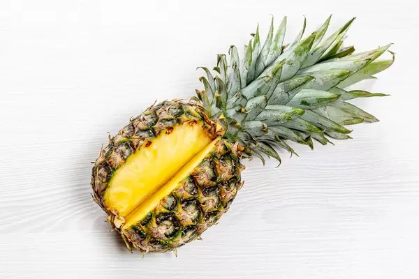 Frische angeschnittene Ananas auf weißem Holzhintergrund