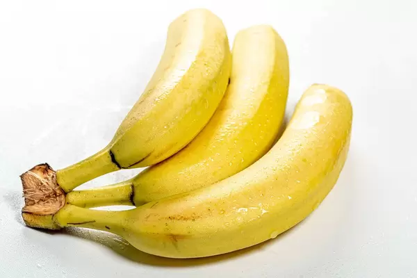 Frische Bananen mit Wassertropfen in weißem Hintergrund