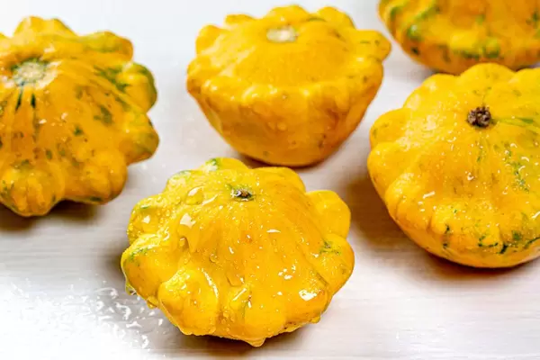 Frische gelbe Kürbisse in interessanter Form, mit Wasserspritzern