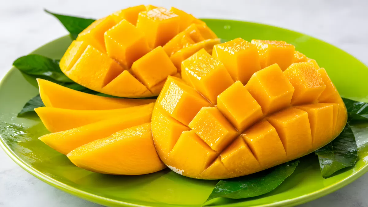 Frische Mangohälften aufgefächert auf grünem Teller