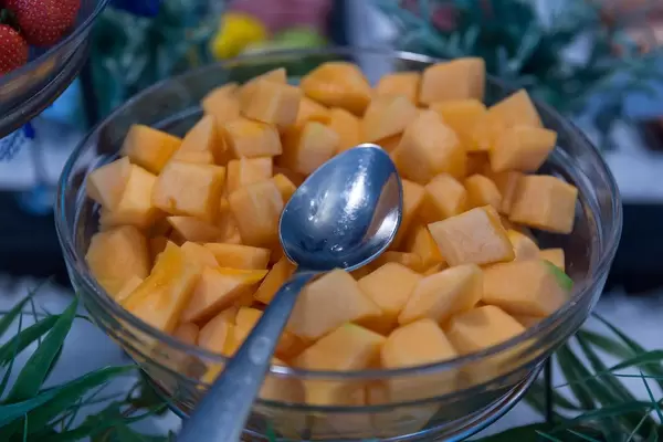 Frische Mangostückchen in einer Glasschüssel mit Löffel am Obst-Büfett