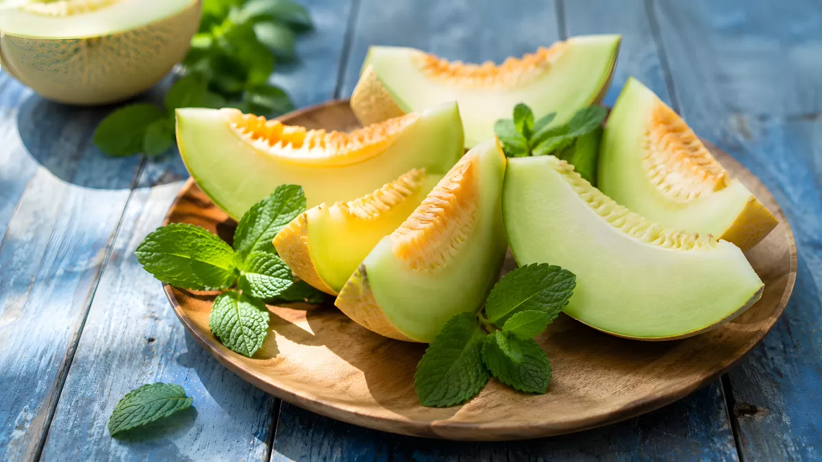 Frische Melonenscheiben auf Holzteller mit Minze