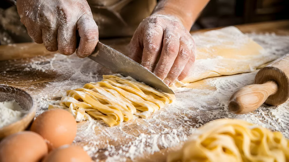 Frische Pasta von Hand schneiden auf bemehlter Arbeitsfläche
