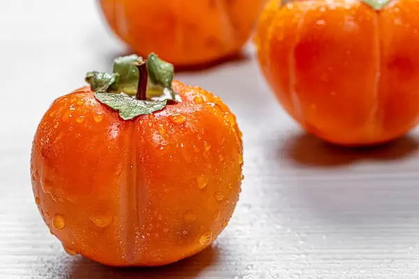 Frische, reife, orangene Persimonen mit Wassertropfen auf der Haut