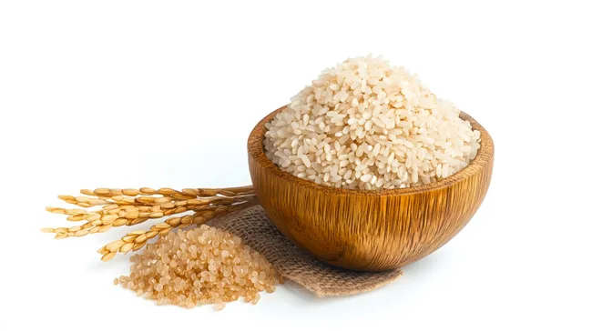 Frische Reiskörner in Holzschale mit Reisähren