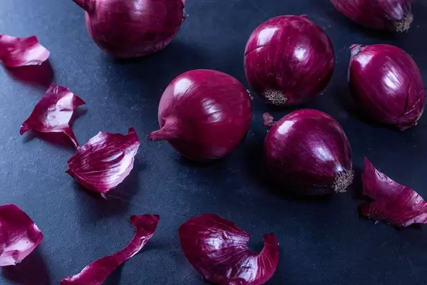 Frische rohe rote Zwiebel auf schwarzer Tabelle