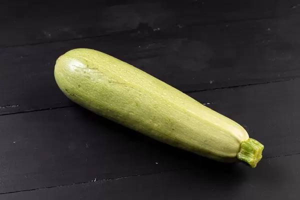 Frische rohe Zucchini auf der schwarzen Tabelle