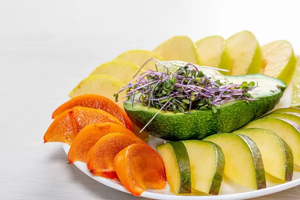 Frische Scheiben von Mango, Kaki, Apfel und Limette mit Kohlkresse