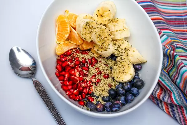 Frischer Fruchtsalat mit Banane, Orange, Blaubeeren, Granatapfel, Hanfsamen