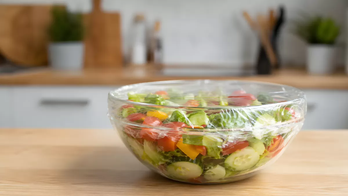 Frischer Gemüsesalat in Glasschüssel mit Frischhaltefolie