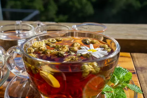 Frischer Kamillentee mit Zitronengras, Minze und Zitronenscheiben in einer Glastasse auf einem Glasuntersetzer in einem Outdoor-Cafe Nahaufnahme