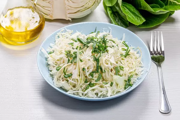 Frischer Kohl- und Lauch Salat mit Oliven-Öl auf weißem Holzhintergrund