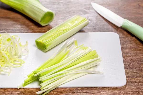 Frischer Lauch auf Küchenbrett mit Keramikmesser