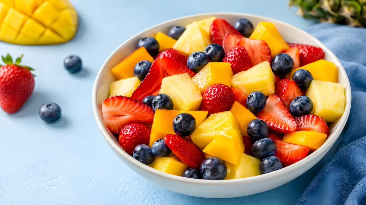 Frischer Obstsalat mit Beeren und Mango in weißer Schale